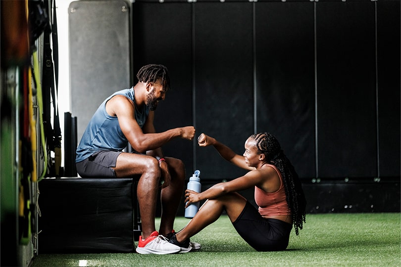 A young man and woman working out together in a gym to help manage heart disease risk and protect heart health