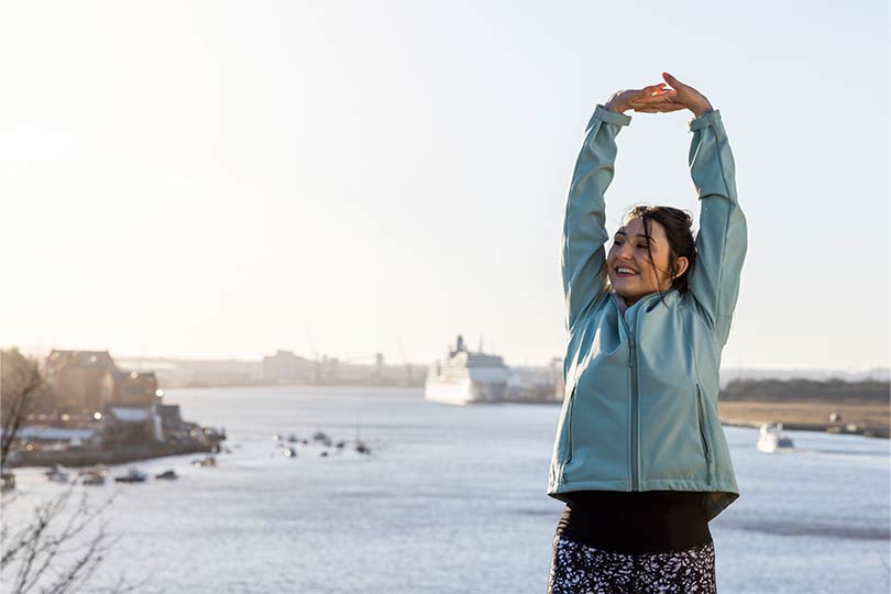 A woman stretching outside, engaging in physical activity to help balance hormone levels naturally. 