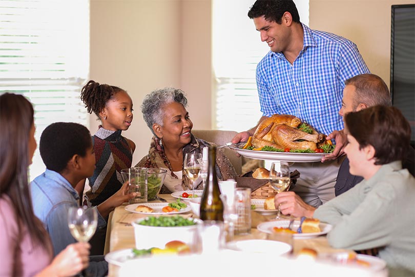 A family gathered around the table for a holiday feast with inclusive food options for people with chronic conditions like food allergies, diabetes, celiac disease or liver disease. 