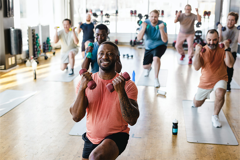 A group of men exercising with free weights in a workout class 