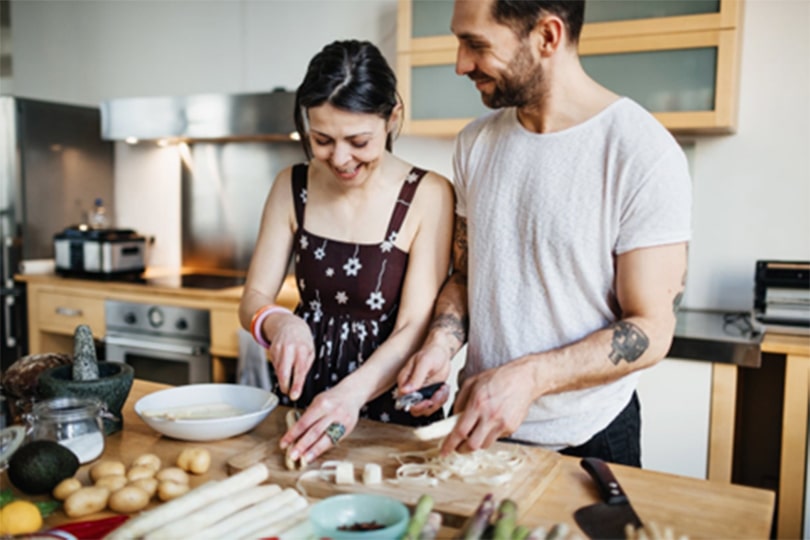 A couple standing in a kitchen preparing food and discussing the importance of STI testing.