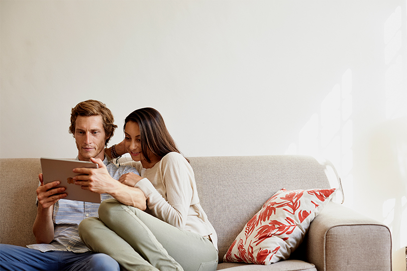 A couple, man and woman, sitting next to each other and smiling, discussing how to prepare for STI testing and navigate the process together.