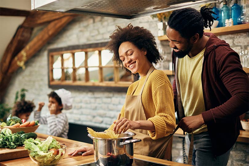 A young family in the kitchen cooking up a healthy meal as part of their New Year’s resolution health goal to improve their diet.