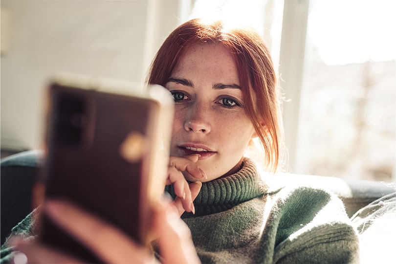 A woman looking at her phone, researching questions about tuberculosis screening