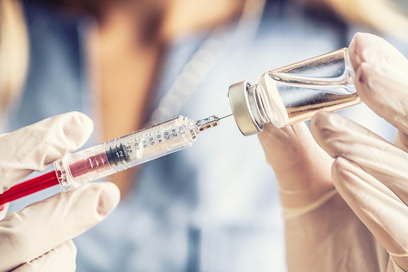 A close-up photo of a healthcare provider holding an infectious disease vaccine needle.