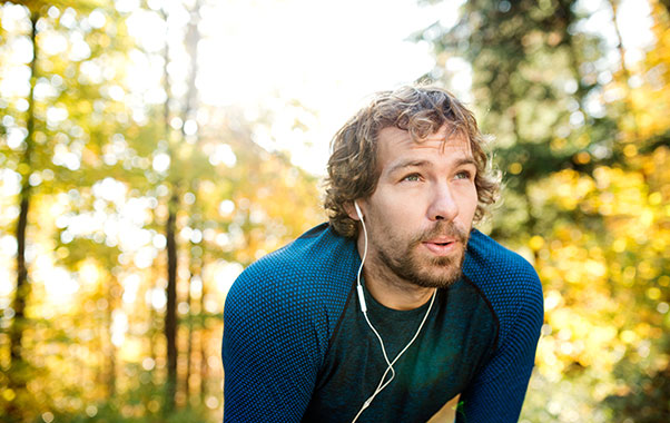 Male runner resting from run in the woods