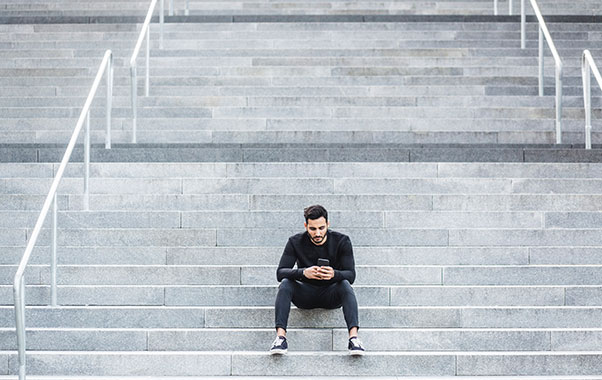 Male sitting on stairs looking at phone