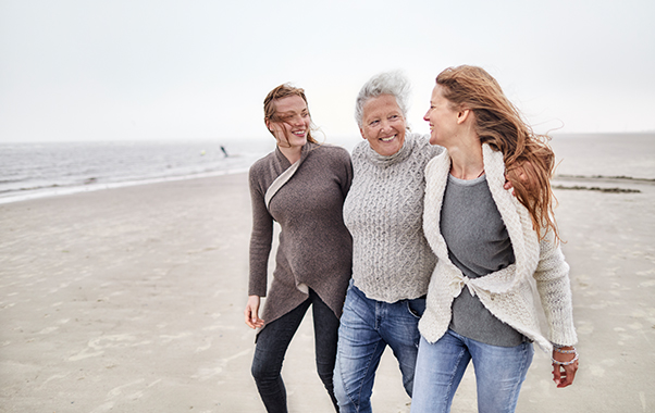 Three women stroll along the beach, enjoying the sun and each other's company.