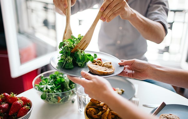 A couple enjoys a fresh salad together, seated at a table, sharing a moment of connection and healthy dining