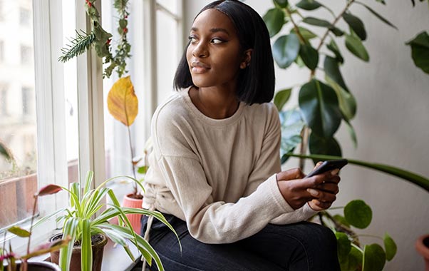 A woman sitting on a window sill tracking their cycle for fertility.