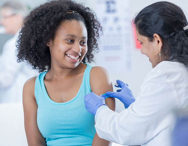 A woman is being vaccinated by a doctor, emphasizing the role of medical professionals in public health initiatives.