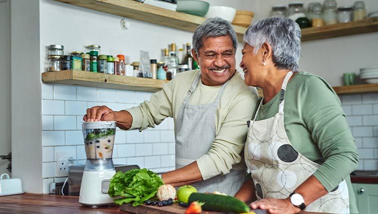 Senior couple preparing a healthy smoothie in the kitchen at home.