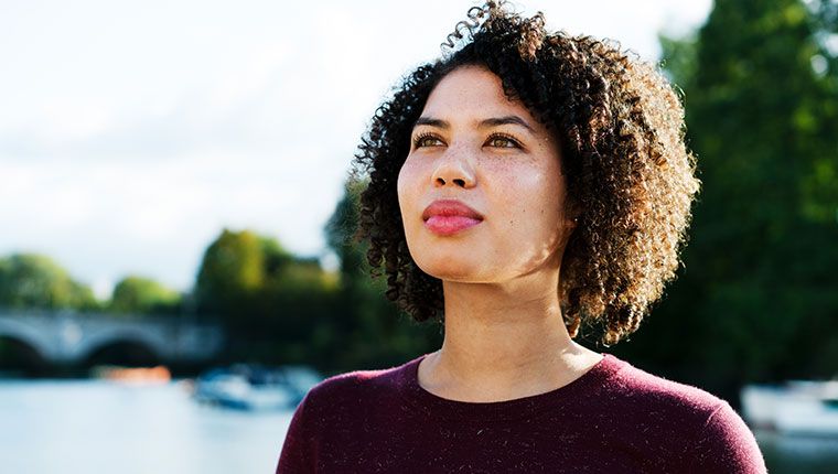 Woman with thoughtful expression standing outdoors