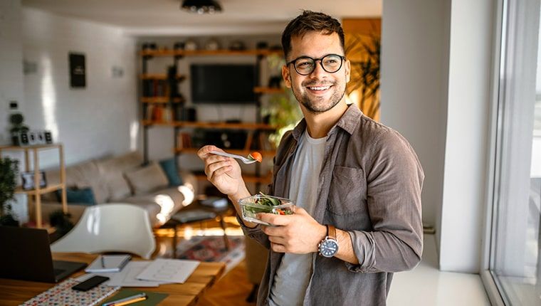 A man in glasses holds a bowl of salad